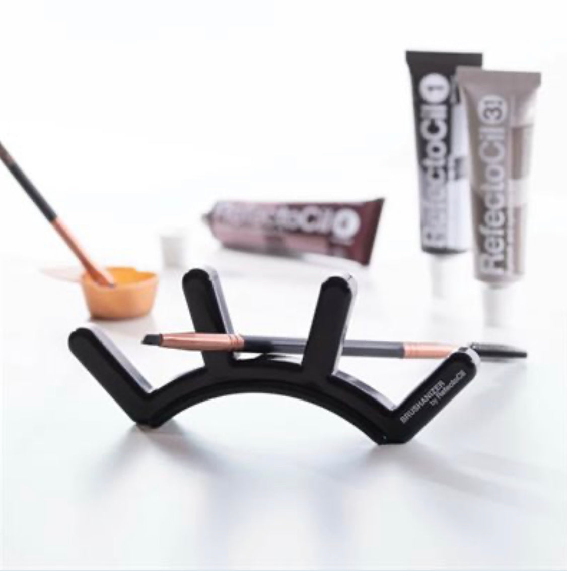 RefectoCil Brushanizer by A & E Beauty Supplies, a hygienic and decorative tool organizer for brow and lash professionals. A black eyebrow shaped holder for brushes.